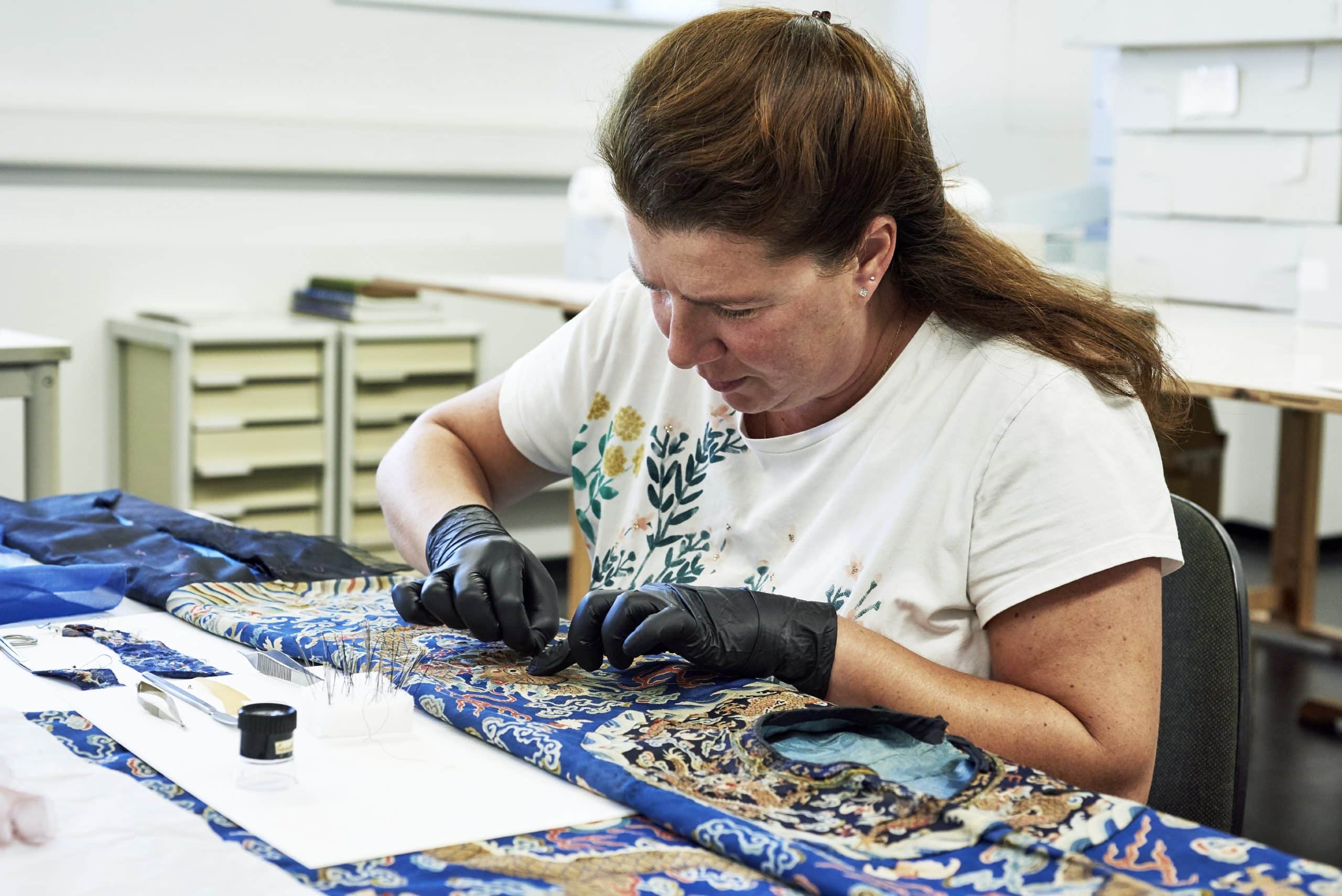 Textilrestauratorin Carola Berriola während der Restaurierung der chinesischen Drachenrobe. Foto: © GRASSI Museum für Angewandte Kunst Leipzig/Karola Bauer